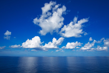 Fototapeta na wymiar Blue sky with white clouds reflex on the sea.