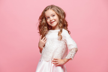 The beautiful little girl in dress standing and posing over white background