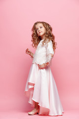 Full length of beautiful little girl in dress standing and posing over white background