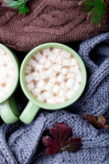 Obraz na płótnie Canvas Two cup of coffee or hot chocolate with marshmallow near three knitted grey, black and brown sweater or knitted blanket. Autumn concept. Christmas. Top view. Warm at home.
