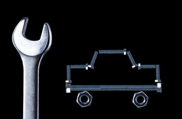 Металлические болты и гайки собраны в образ автомобиля и гаечный ключ.Концепция ремонта.
