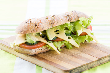fitness sandwich with avocado and cheese on wooden board

