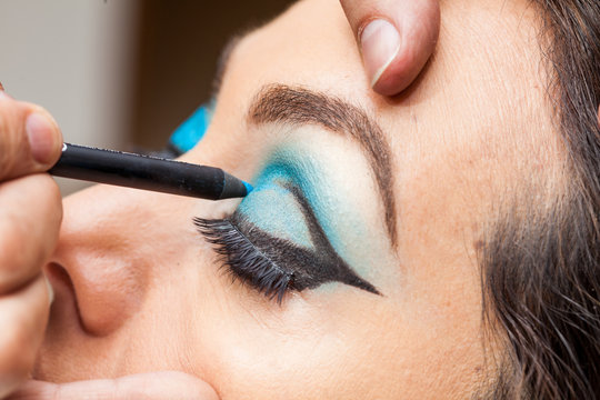 Makeup artist applying blue eyeshadow on white woman eyes