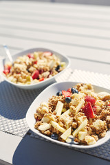 plates with fresh fruit salad, Granola and berries in the morning on the veranda. Delicious, quick and healthy light breakfast for energetic people