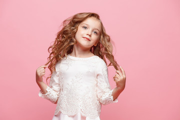 The beautiful little girl in dress standing and posing over white background