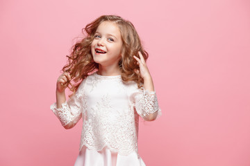 The beautiful little girl in dress standing and posing over white background