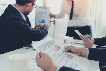 Business team during meeting conference are working documents about the marketing plan and sales profit finance of the company with laptop computer and smartphone tablet on work table