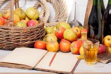 basket of apples, bottles of cider and old notebook