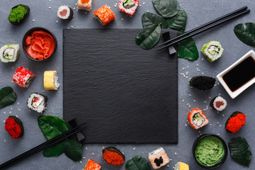 Square black slate plate with sushi on rustic grey backround, copy space