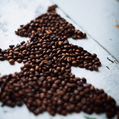 Shape of christmas tree made of coffee beans on wooden table. Top view, copy space. Winter holidays concept