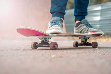 Red skate Legs in sneakers. Sports, teenager, riding area.