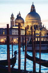 Fototapeta na wymiar Gondolas moored by Saint Mark square with Cathedral of Santa Maria della Salute on background