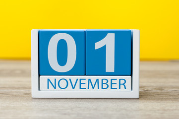 November 1st. Day 1 of month, wooden color calendar on yellow background. Autumn time