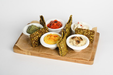 Appetizer of hummus, guacamole, veggie salsa, creamy cheese with sundried tomatoes and julienne with mushrooms with bread on a wooden desk isolated on white background