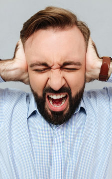 Vertical image of screaming bearded man in business clothes