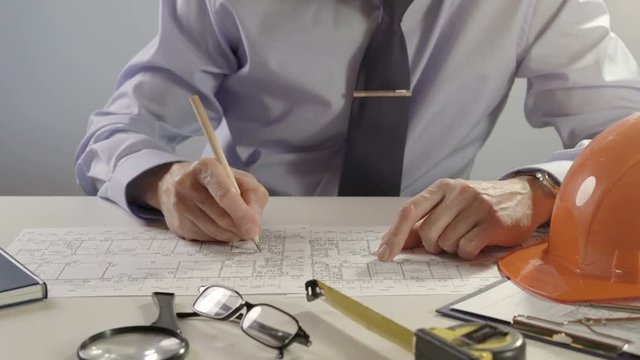 Architect or engineer using pencil working on blueprint, architectural concept