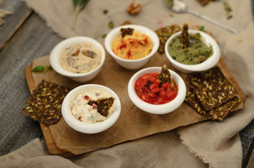 Appetizer of hummus, guacamole, veggie salsa, creamy cheese with sundried tomatoes and julienne with mushrooms with bread on a wooden desk
