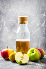 Detox apple cider drink in a bottle and fresh apples on stone background. Selective focus, space for text. 