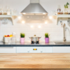 A wooden table top of the kitchen table on a blurry background of the kitchen interior. Bright interior decoration of home cooking. Bright ready-made picture for your individual design