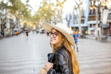 Obraz premium Young woman tourist in hat walking on the famous pedestrian boulevard in Barcelona city