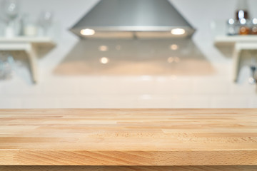 A wooden table top of the kitchen table on a blurry background of the kitchen interior. Bright interior decoration of home cooking. Bright ready-made picture for your individual design