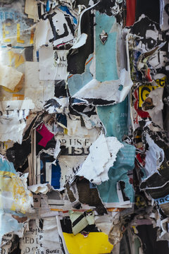 Layers of torn and peeling posters attached to telephone pole, close up