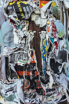 Layers of torn and peeling posters attached to telephone pole, close up