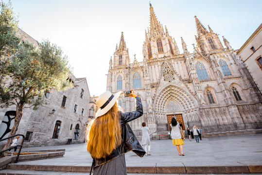 Young woman tourist photographing with phone famous saint Eulalia church during the morning light in Barcelona city