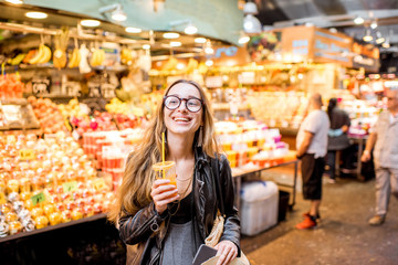 Fototapeta premium Młoda kobieta pije sok pomarańczowy na słynnym targu spożywczym w Barcelonie