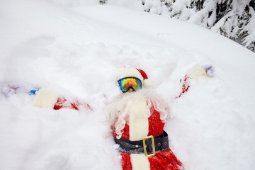 Santa Claus lies on the snow in winter for Christmas.