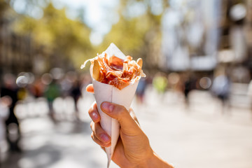 Obraz premium Holding jamon traditional spanish jerked meat outdoors on the street in Barcelona