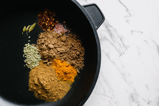 ground spices in a frypan on a marble background