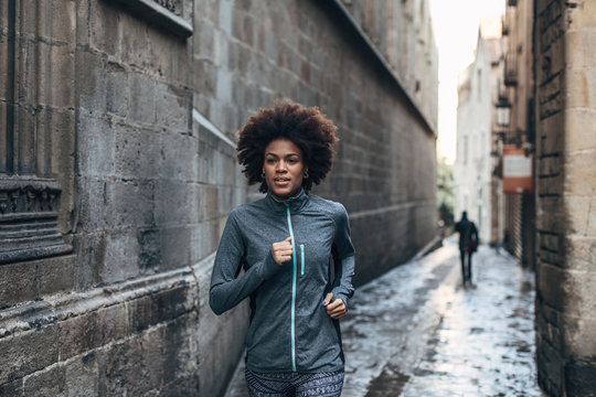 Young african american woman running on Barcelona streets.