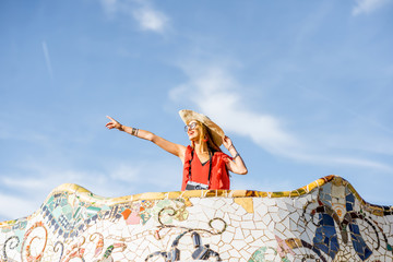 Fototapeta premium View on the beautiful terrace decorated with mosaic with happy woman tourist in Guell park in Barcelona