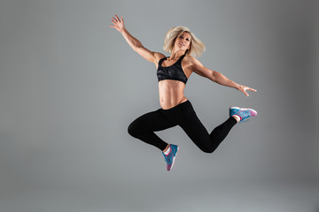 Fototapeta na wymiar Full length portrait of a smiling muscular adult woman jumping