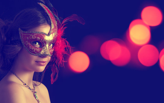 Beautiful woman in carnival mask on a background of holiday lights.