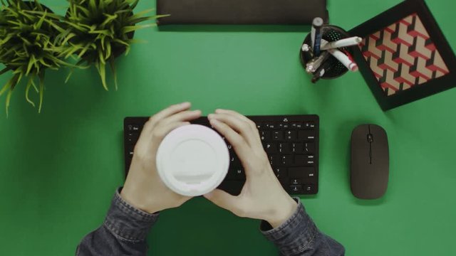 Top down shot of man drinking tea while working on computer