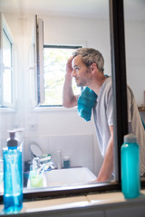  Handsome gray haired man examining his hair in the bathroom
