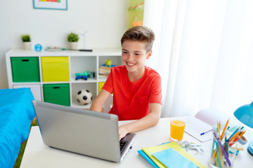 student boy typing on laptop computer at home
