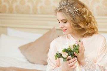 Beautiful young Bride with blonde hairs in a bedroom. Classic white wedding dress. Half-length portrait