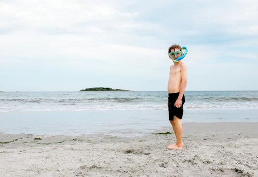 Boy at the beach wears snorkel and mask