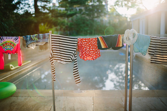childrens' swimsuits hang to dry beside a pool in the summertime