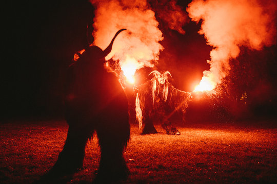 two krampus making fire show with bengal light