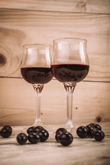 Two glasses of red wine and grapes on wooden table