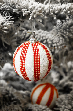 Two striped balls hanging on Christmas tree covered with snow. Vintage Christmas card. Toned photo.