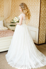 Fototapeta premium Beautiful young Bride with blonde hairs in a bedroom. Classic white wedding dress. Half-length portrait