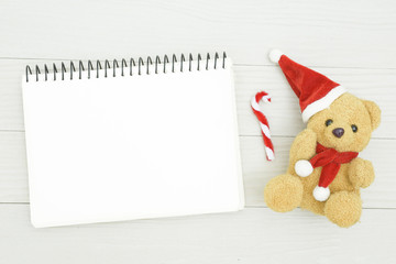 Christmas bear and white book with top view and copy space on the white wooden table. Christmas holiday concept.