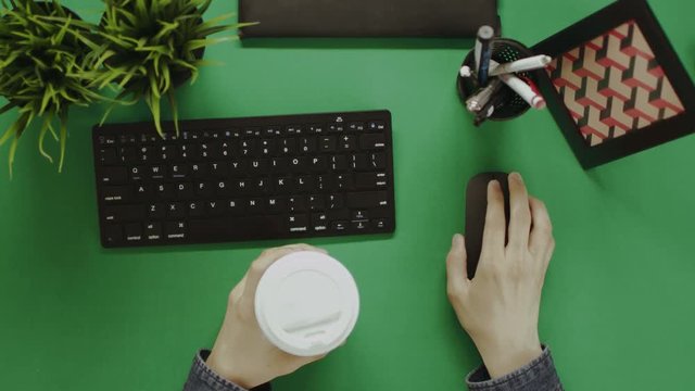 Top down shot of man working on computer while drinking tea