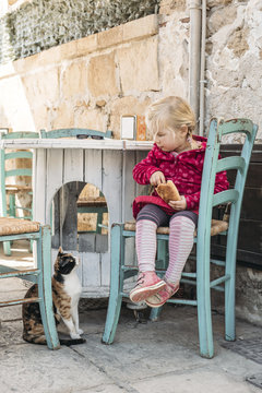 People: Little girl sharing her food with a hungry cat