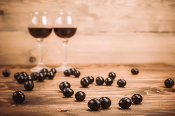 Two glasses of red wine and grapes on wooden table